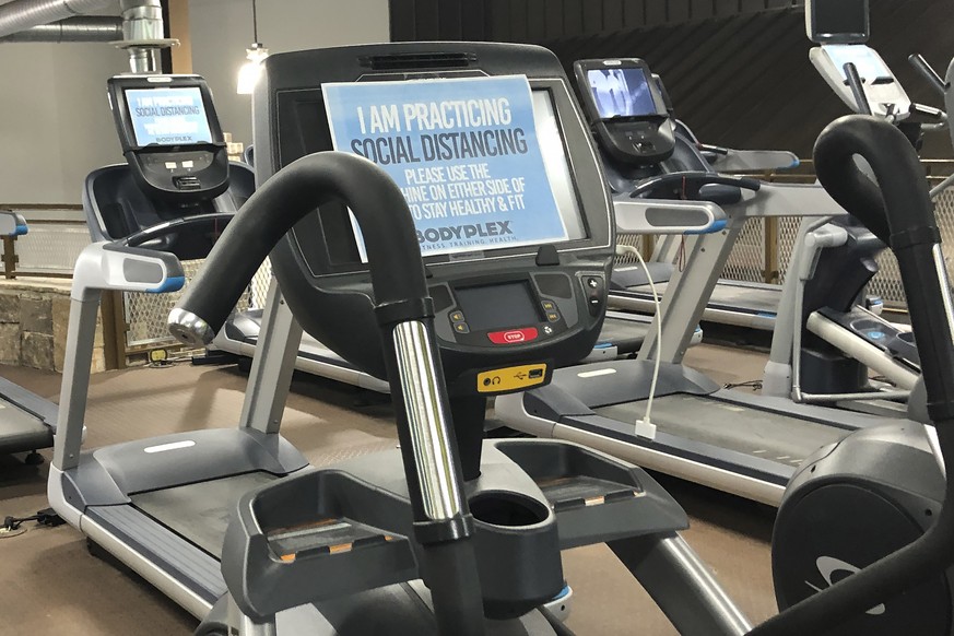 A sign on posted on gym equipment, advises patrons to practice social distancing amid the COVID-19 virus outbreak at Bodyplex Fitness Adventure on Friday, April 24, 2020, in Grayson, Ga. Gov. Brian Ke ...