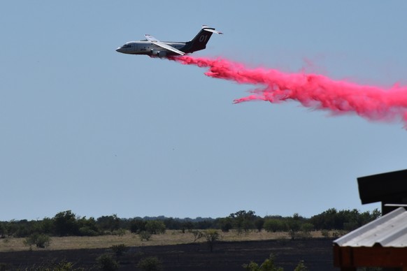 A tanker aircraft dumps fire retardant on a field southwest of Salado, Texas, Wednesday, Aug. 12, 2026, after a military helicopter crashed and sparked a grass fire. (Brent Johnson/The Killeen Daily H ...