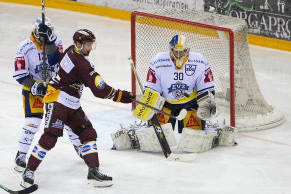Zug&#039;s goaltender Leonardo Genoni, right, saves a puck past Zug&#039;s forward Yannick Zehnder, left, and Geneve-Servette&#039;s forward Tyler Moy, center, during the second leg of the National Le ...