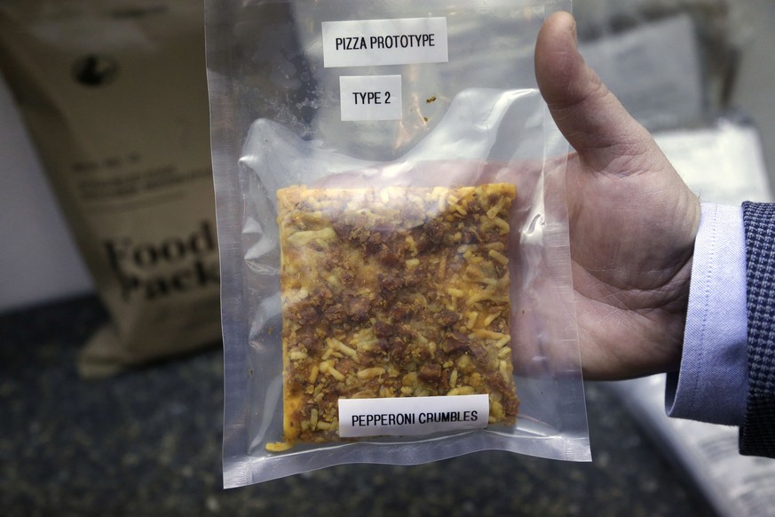 In this Thursday, Feb. 6, 2014 photo, a packet containing a slice of prototype pizza is displayed by public affairs officer David Accetta at the U.S. Army Natick Soldier Research, Development and Engi ...