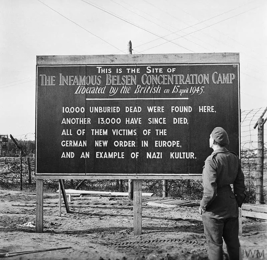 A soldier stands in front of a sign erected by British Forces at the entrance to Bergen-Belsen concentration camp, Germany, May 1945