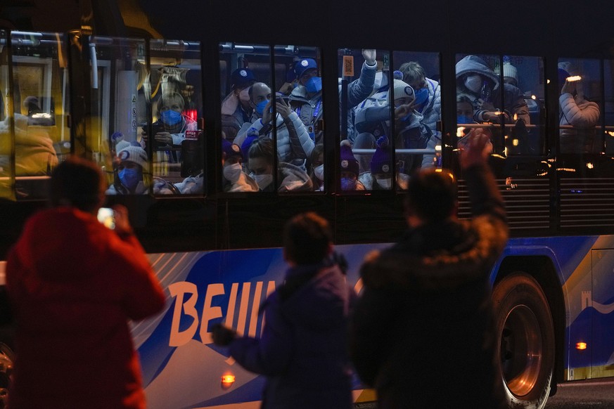 Foreign athletes inside a bus respond to residents on a street as they were heading to the National Stadium ahead of the opening ceremony of the 2022 Winter Olympics, in Beijing, Feb. 4, 2022. (AP Pho ...