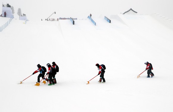 epa09751354 Grounds crew maintain the slopes during a delay ahead of the Women&#039;s Freestyle Skiing Slopestyle qualification at the Zhangjiakou Genting Snow Park at the Beijing 2022 Olympic Games,  ...