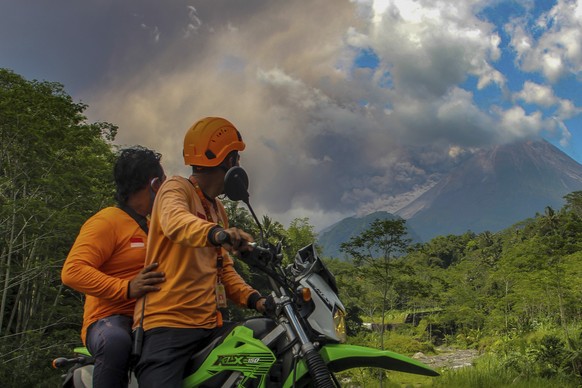 Men watch as Mount Merapi releases volcanic materials during an eruption in Sleman, Indonesia, Saturday, March 11, 2023. (AP Photo/Slamet Riyadi)