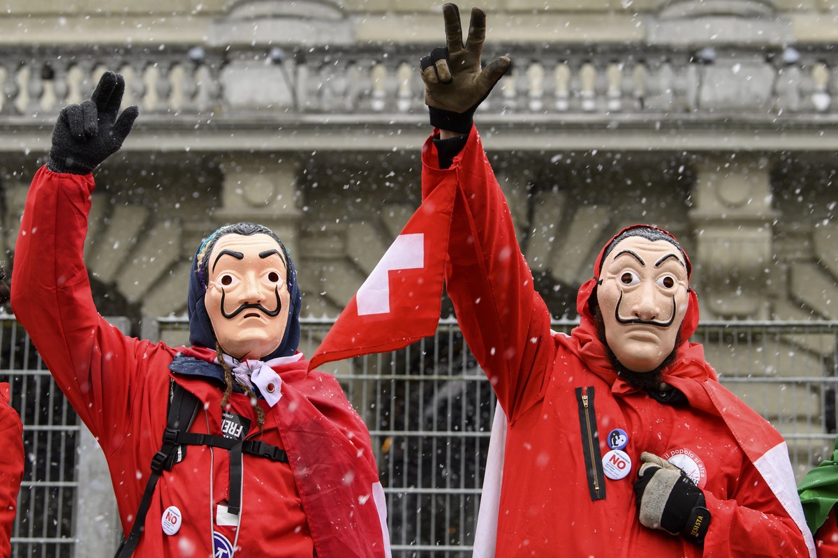 epa09609279 People in costumes of the Spanish streaming series 'Casa del Papel (Money Heist) protest during a rally of opponents of the Covid-19 lawon the Bundesplatz in Bern, Switzerland, 28 Nov ...
