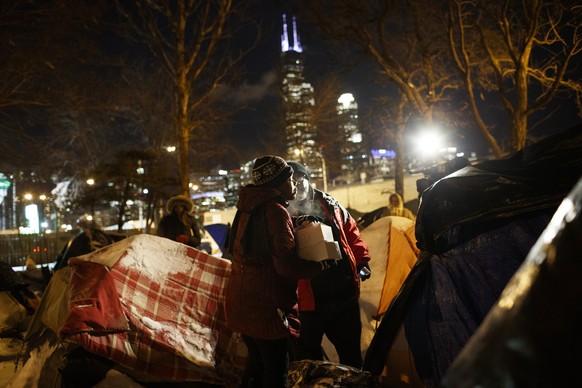 Richard Vargas of the Salvation Army gives a woman food who was sleeping in a tent near a wooded area adjacent to the Dan Ryan Expressway Tuesday Jan. 29, 2019, in Chicago. Vargas visited several loca ...