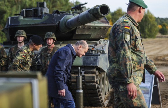 epa10248436 German Chancellor Olaf Scholz passes under the gun barrel of a Leopard 2 tank during a media presentation for the annual Land Operation Exercise of the German armed forces Bundeswehr in Be ...