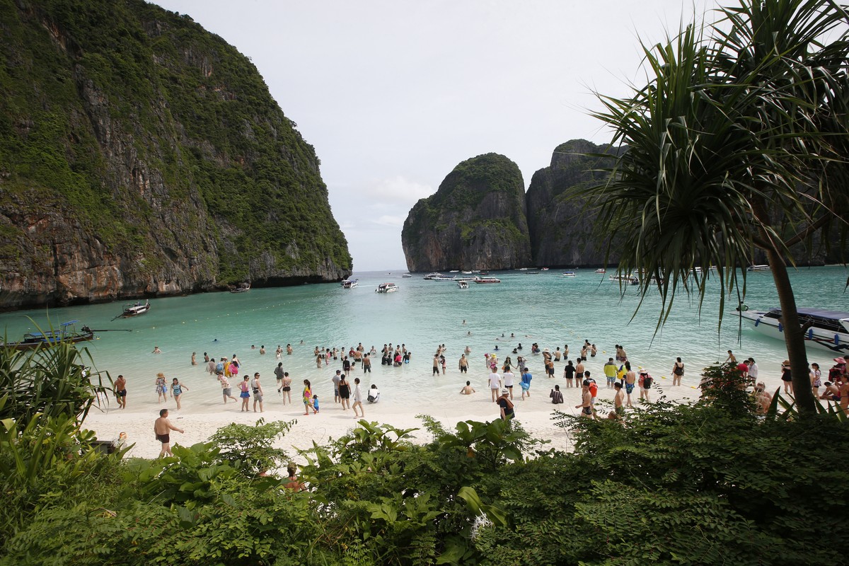 FILE - In this May 31, 2018, file photo, tourists walk the beach of Maya Bay, Phi Phi Leh island in Krabi province, Thailand. The American Society of Travel Agents is starting to refer to agents as &# ...