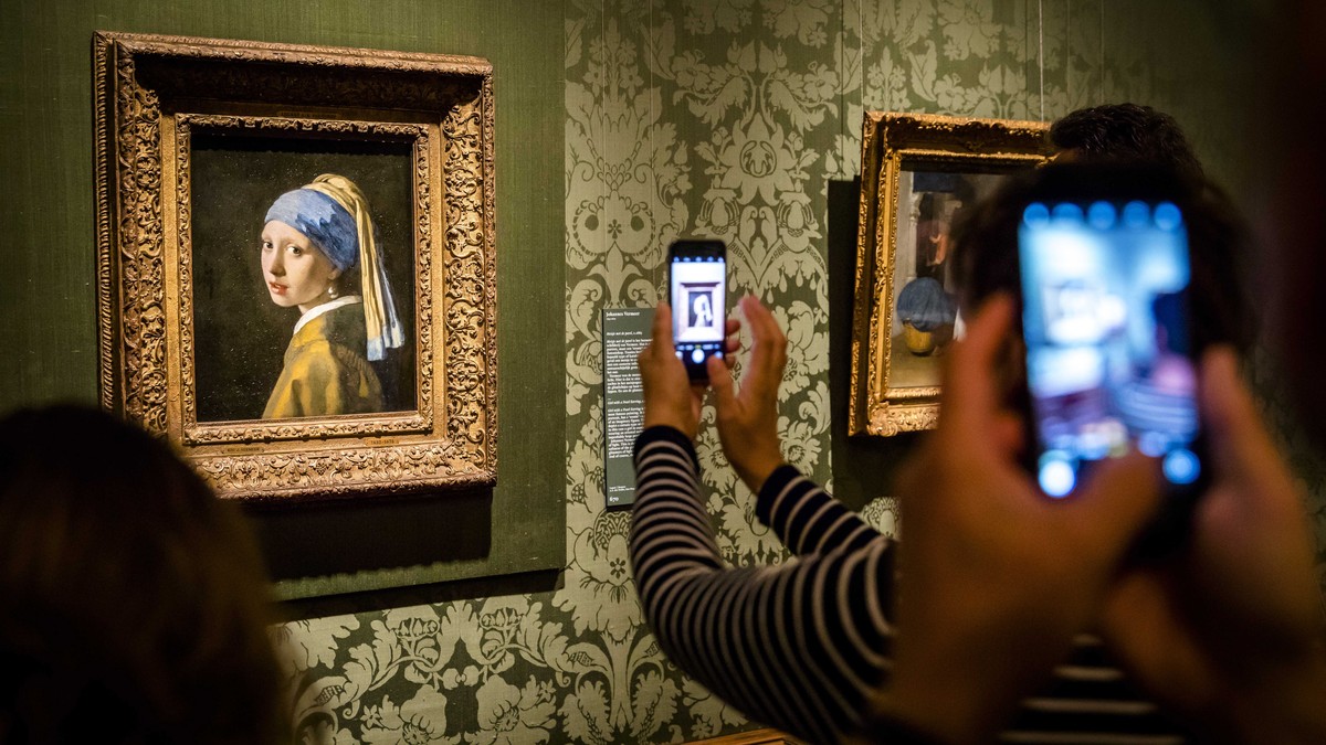 epa10269062 Visitors take photographs of the 'Girl with a Pearl Earring' by Dutch artist Johannes Vermeer in the Mauritshuis Museum in The Hague, The Netherlands, 27 October 2022. The Maurit ...