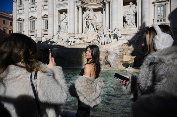 epa12700236 A woman poses at the Trevi Fountain basin on the first day of paid admission in Rome, Italy, 02 February 2026. Starting 02 February, the city will charge tourists and non-residents two eur ...