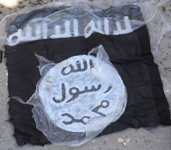 This photo provided by the Kurdish-led Syrian Democratic Forces shows the flag and bags of Islamic State group fighters who were arrested by the Kurdish-led Syrian Democratic Forces after they attacke ...