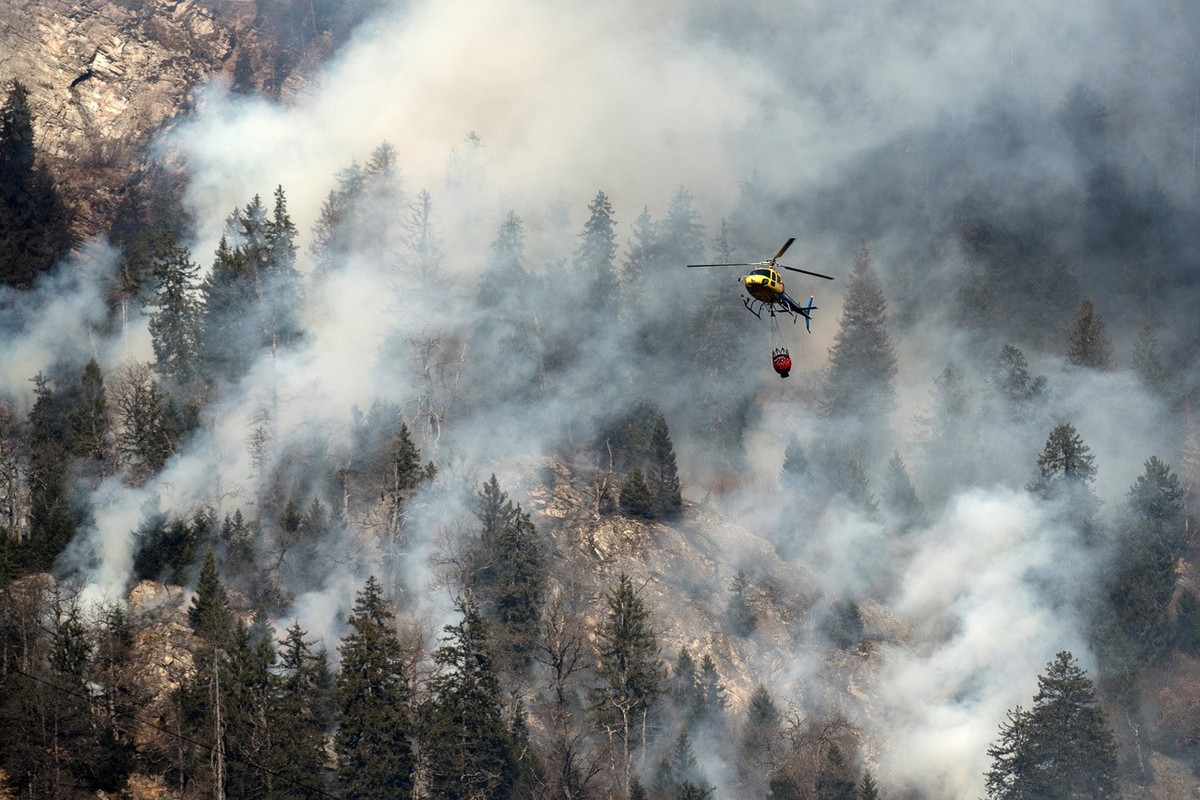 A fire fighting helicopter discharges water over the forest fires near Mesocco in Southern Switzerland, Wednesday, December 28, 2016. (KEYSTONE/Ti-Press/Gabriele Putzu)