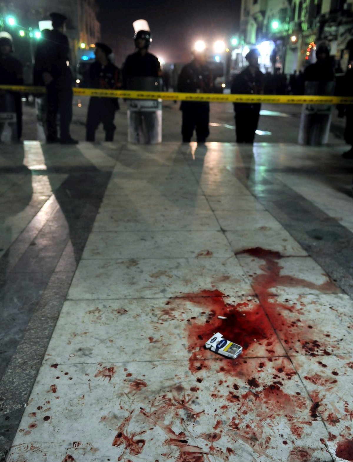 epa01644614 The ground is bloodstained as Egyptian police stand guard outside the Al-Husseini mosque in the Khan el-Khalili market following a bomb blast in Cairo, Egypt on 22 February 2009. A bomb th ...