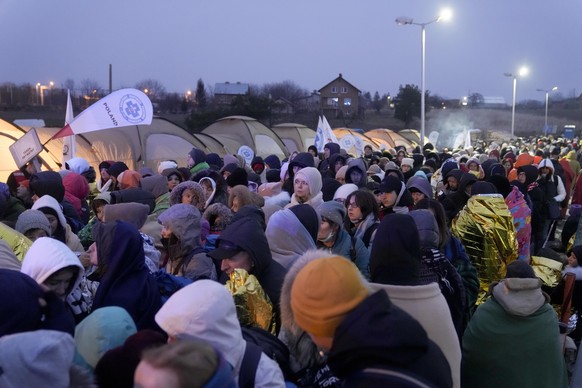 Refugees wait in a crowd for transportation after fleeing from the Ukraine and arriving at the border crossing in Medyka, Poland, Monday, March 7, 2022. Hundreds of thousands of Ukrainian civilians at ...