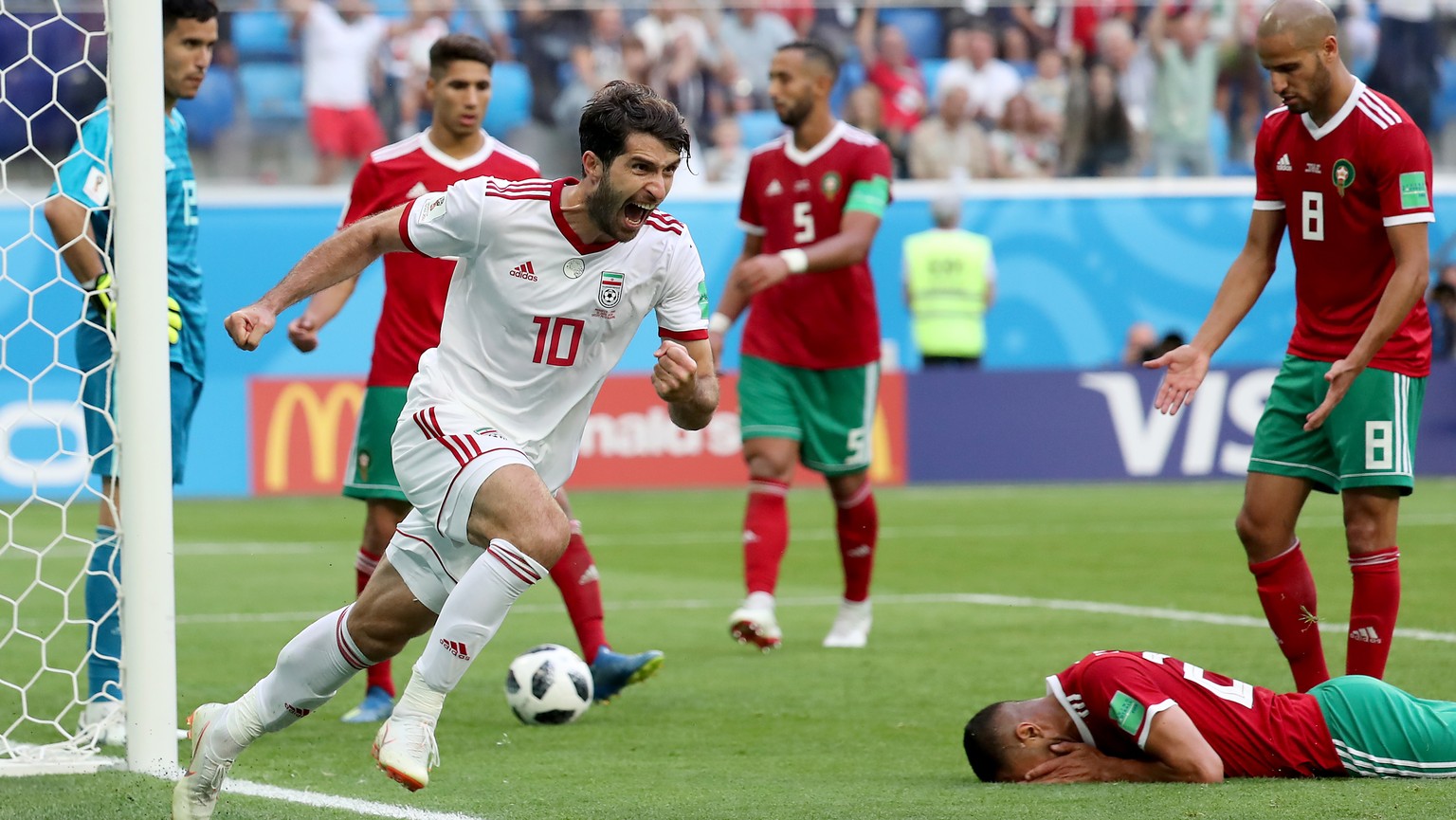 epa06810835 Karim Ansarifard of Iran (front) celebrates after Aziz Bouhaddouz of Morocco (down) scored an own goal during the FIFA World Cup 2018 group B preliminary round soccer match between Morocco ...