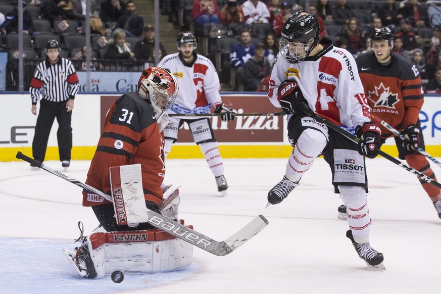 Canada goaltender Carter Hart makes a save in front of Switzerland&#039;s Nico Hischier during the second period of an exhibition game ahead of the IIHF World Junior hockey championships, in Toronto o ...