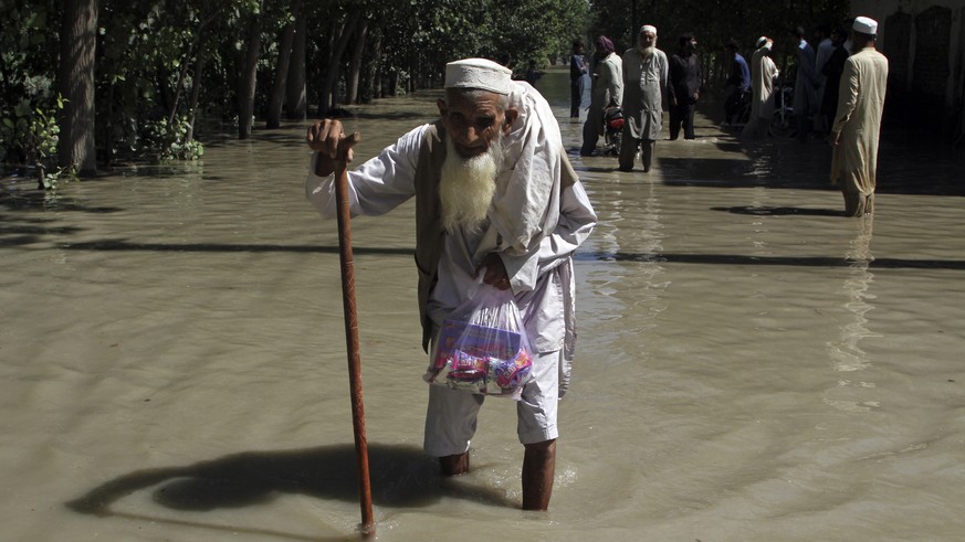FILE - A displaced man wades through a flooded area after fleeing his flood-hit home, on the outskirts of Peshawar, Pakistan, Aug. 28, 2022. The flooding has all the hallmarks of a catastrophe juiced  ...