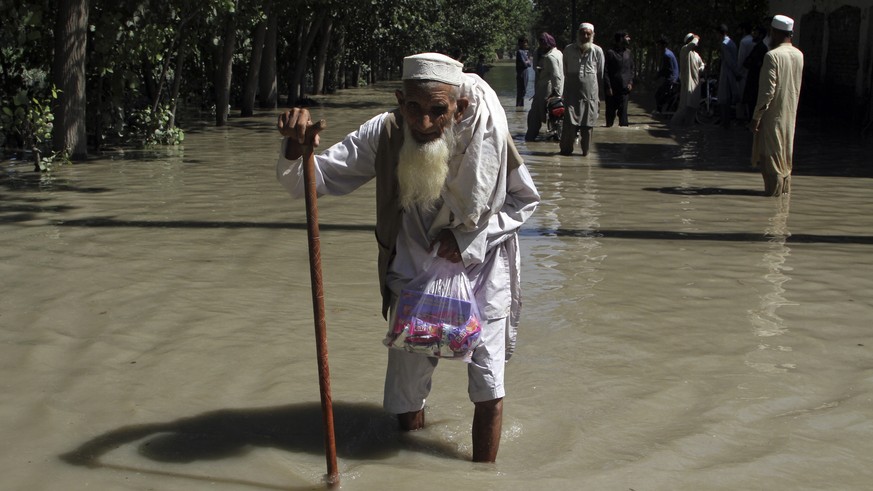 FILE - A displaced man wades through a flooded area after fleeing his flood-hit home, on the outskirts of Peshawar, Pakistan, Aug. 28, 2022. The flooding has all the hallmarks of a catastrophe juiced ...