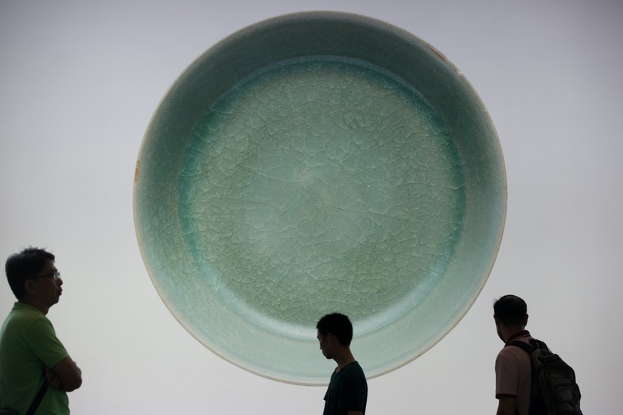 epa06240918 People walk past a giant poster of a Ru Guanyao Brush Washer from Northern Song Dynasty during the Chinese Works of Art Autumn Sales in Hong Kong, China, 03 October 2017. The 900-year-old  ...