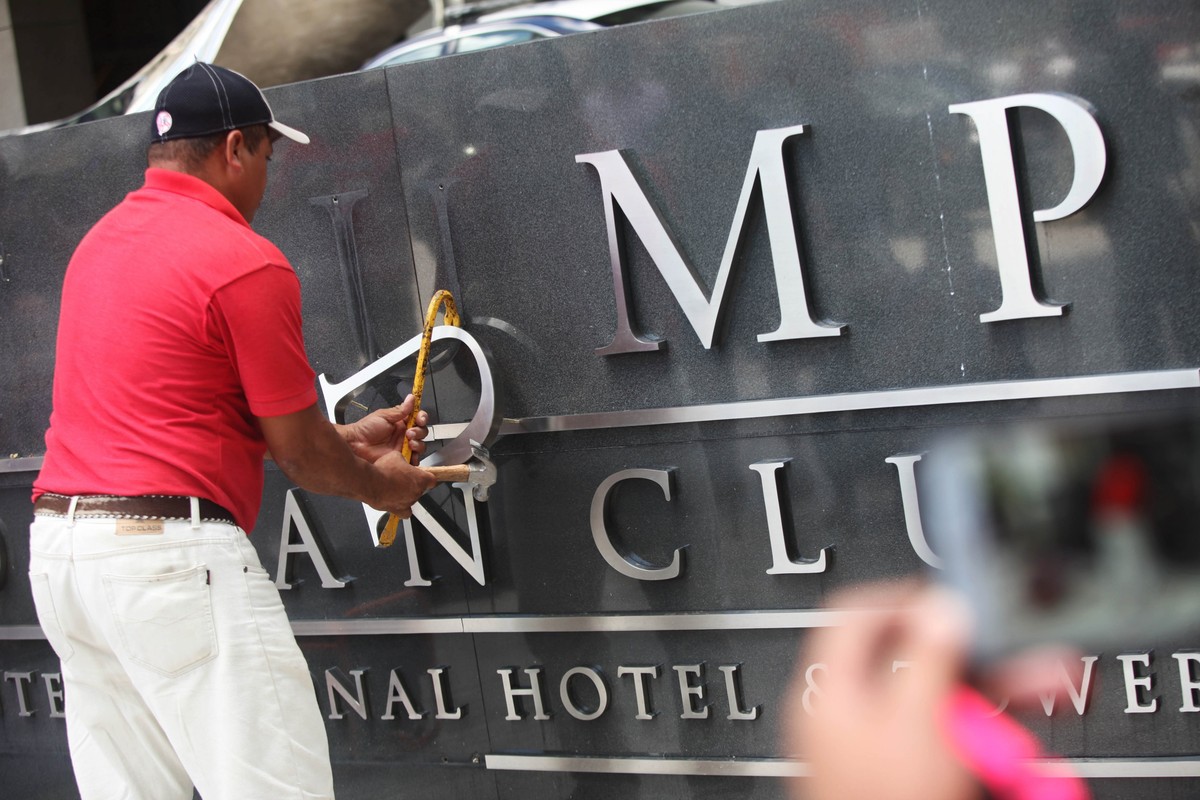 epa06583505 A worker removes the Ocean Club Trump Hotel's sign as authorities conduct an operation at the facilities of the Ocean Club Trump Hotel in Panama City, Panama, 05 March 2018. A Panaman ...