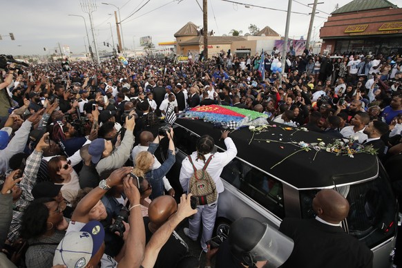 A hearse carrying the casket of slain rapper Nipsey Hussle, draped in the flag of his father’s native country, Eritrea in East Africa, passes through the crowd Thursday, April 11, 2019, in Los Angeles ...