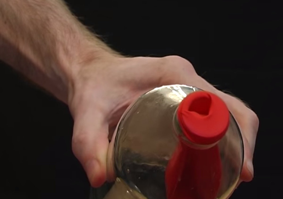 Stopf den Ballon in die Flasche und stülpe den vorderen Teil über den Flaschenrand. Dann bitte deinen Freund, ihn aufzublasen.&nbsp;