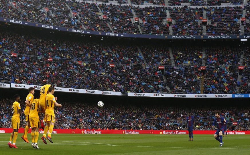 FC Barcelona&#039;s Lionel Messi, right, shoots a free kick during the Spanish La Liga soccer match between FC Barcelona and Atletico Madrid at the Camp Nou stadium in Barcelona, Spain, Sunday, March  ...