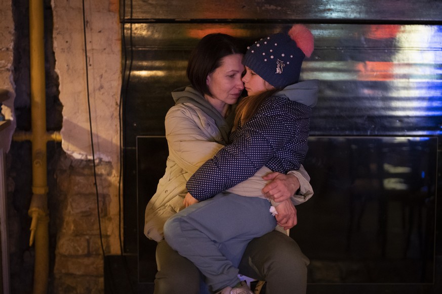 A woman holds her daughter as they sit in a basement used as a bomb shelter in Kyiv, Ukraine, Thursday, Feb. 24, 2022. (AP Photo/Emilio Morenatti)