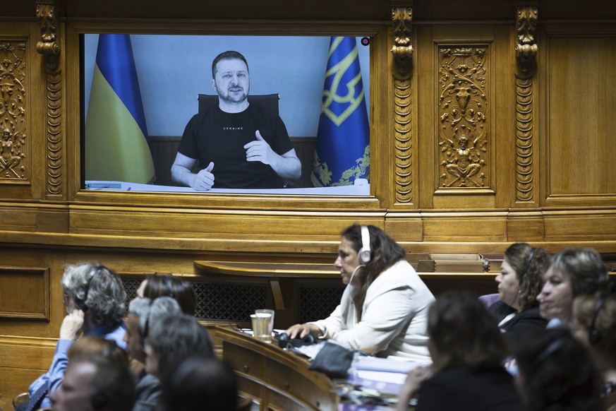 Ukrainian President Volodymyr Zelenskyy is shown on screen during his speech to members of the Swiss Parliament, in Bern, Switzerland, Thursday, June 15, 2023. (Peter Klaunzer/Keystone via A…