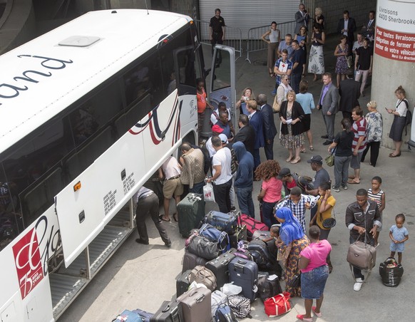 A busload of asylum seekers arrives at Olympic Stadium Thursday, August 3, 2017 in Montreal. The stadium is being used as temporary housing to deal with the influx of asylum seekers arriving from the  ...