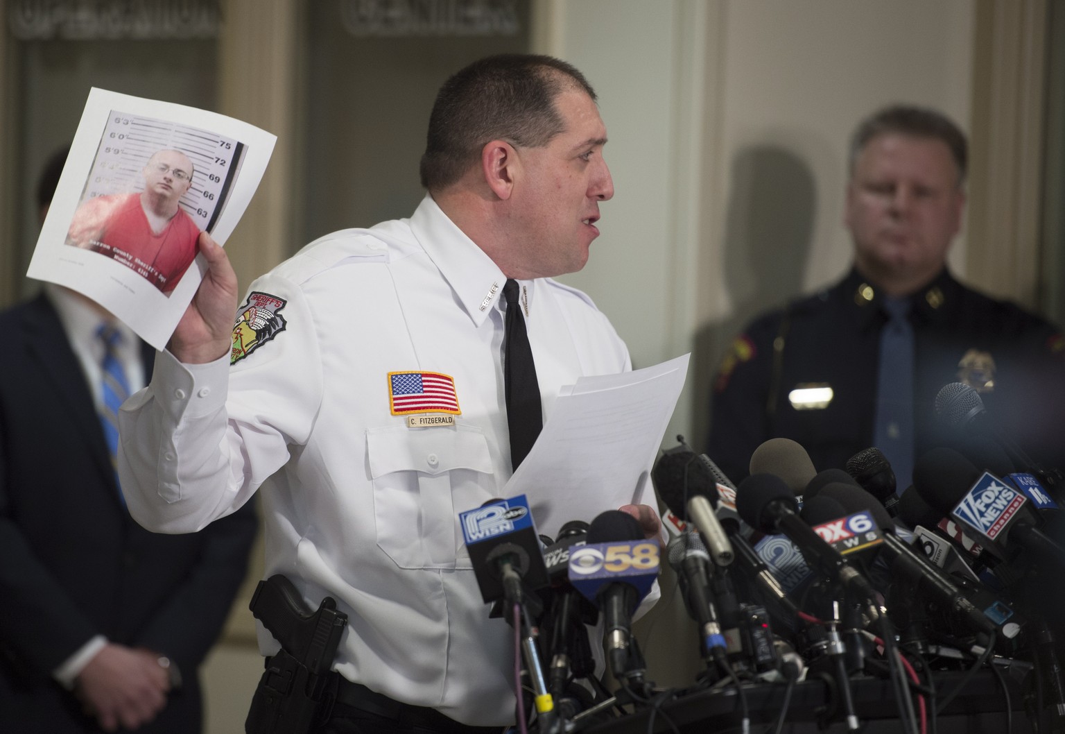 epa07275829 Baron County Sheriff Chris Fitzgerald holds up a photo of the suspect, Jake Thomas Patterson, as he announces that Jayme Closs was found alive, during a news conference in Baron, Wisconsin ...