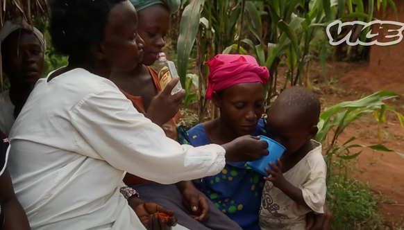 Frauen geben einem Kleinking in Uganda &quot;Waregi&quot;, selbstgebrannter Alkohol, zum Trinken.