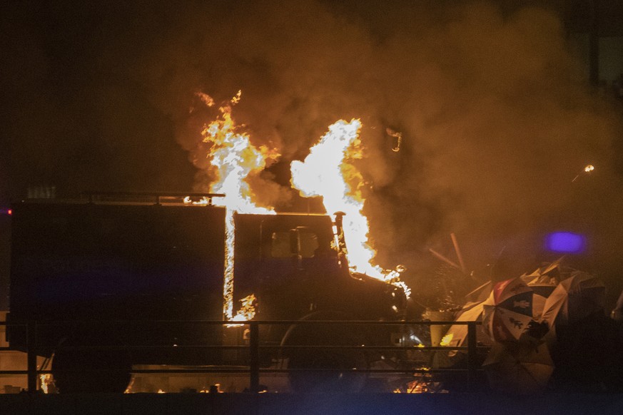 In this Sunday, Nov. 17, 2019, photo, an armored police truck tries to breach a barricade outside the Hong Kong Polytechnic University in Hong Kong. Fiery explosions were seen early Monday as Hong Kon ...