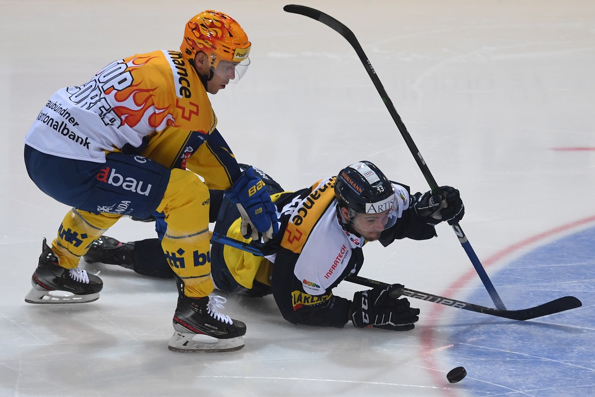Davos's player Perttu Lindgren, left, fights for the puck with Ambri's player Marco Mueller, right, during the preliminary round game of National League Swiss Championship between HC Ambri P ...