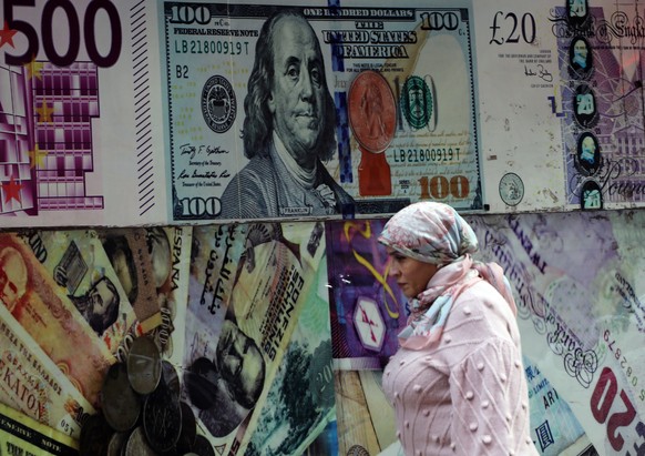 epa11202004 A woman walks past a large-scale image of a US dollar banknote on a currency exchange office in Cairo, Egypt, 06 March 2024. Egypt&#039;s pound hit an all-time low after the Central Bank o ...
