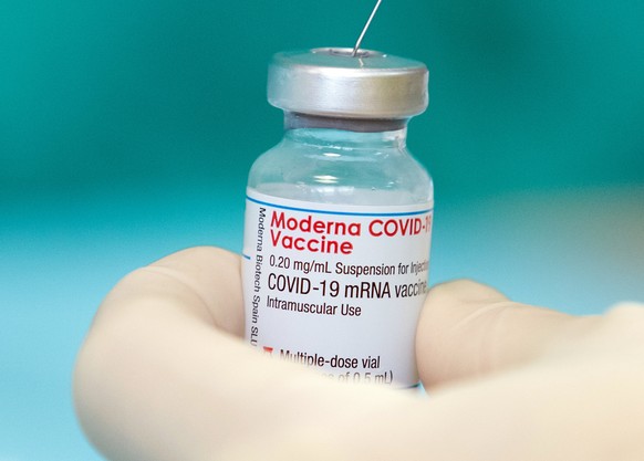 ARCHIV - 16.04.2021, Nordrhein-Westfalen, Bielefeld: Eine Krankenschwester zieht den Impfstoff des Herstellers Moderna gegen das Coronavirus in einer gestellten Situation mit einer Spritze auf. (zu dp ...