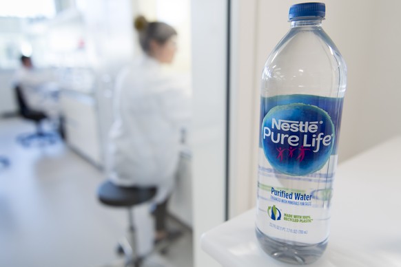 epa07837554 A prototype of a water bottle made out of recycled plastic is pictured in front of staff working in a laboratory during the inauguration of Nestle Institute of Packaging Sciences at the Ne ...