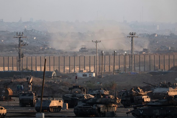 epaselect epa12416154 Israeli troops (front) stationed along the northern part of the Israel-Gaza border, as Israeli tanks (back) operate inside the Gaza Strip, as seen from an undisclosed location in ...