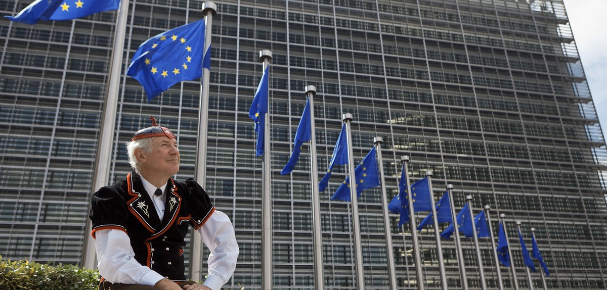 Flags of the European Union wave in front of the European Commission building in Brussels, June 8, 2011, while "Mister Swiss", dressed in a traditional Swiss costume, looks on. He is on his  ...