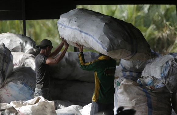 epa09079127 Workers sort plastic waste before processing into raw material of plastic at a plastic waste bank in Banda Aceh, Indonesia, 17 March 2021. The sorted plastic waste will be milled into smal ...