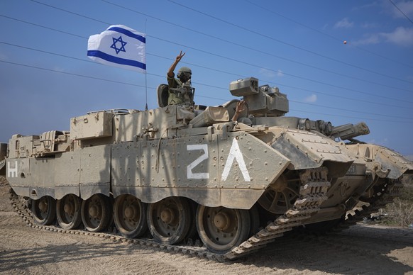 An Israeli soldier flashes a V-sign from an armoured personnel carrier (APC) as they head towards the Gaza Strip border in southern Israel, Saturday, Oct. 14, 2023. (AP Photo/Ariel Schalit)