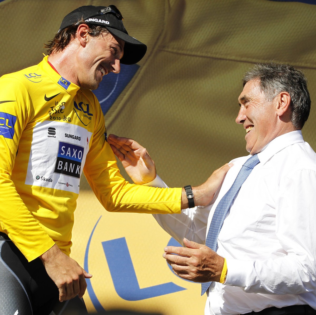 Fabian Cancellara of Switzerland, wearing the overall leader's yellow jersey, left, and Belgium cyclist and Tour de France winner Eddy Merckx, right, react on the podium after the first stage of  ...