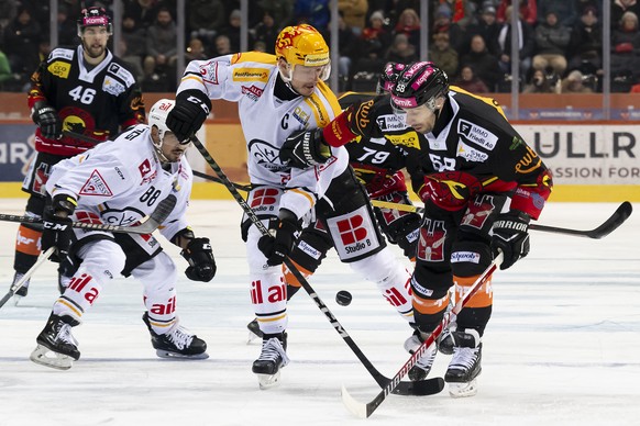 Lugano PostFinance Top Scorer Calvin Thuerkauf, Mitte, und der Berner Spieler Romain Loeffel, rechts, kaempfen um den Puck, beim Eishockey Meisterschaftsspiel der National League zwischen dem SC Bern  ...