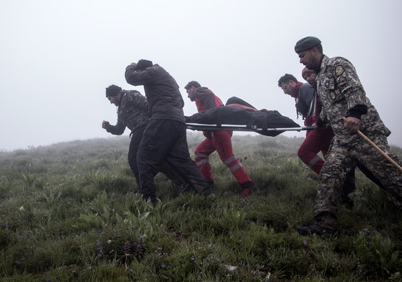 epa11354945 Iranian rescue workers carry the bodies of the victim of the crashed Iranian President helicopter, in the area of Varzaghan, Tabriz province, southwestern Iran, 20 May 2024. According to I ...