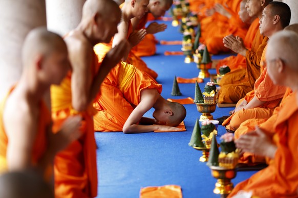 epa12204364 Newly ordained hill tribe Buddhist monks (L) pay respects after receiving the precepts from senior monks during the 60th annual mass Buddhist monk ordination ceremony for hill tribe men an ...
