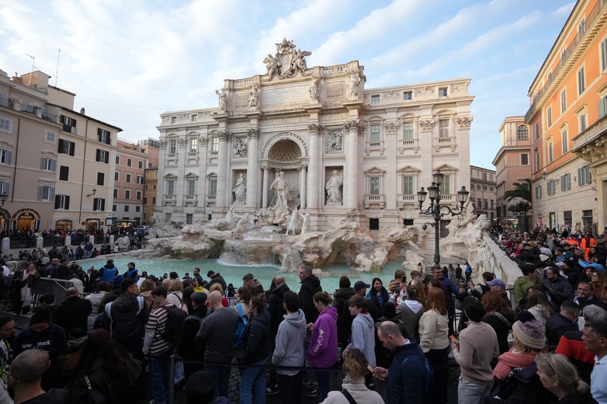 Visitors admire Rome's Trevi Fountain, Friday, Dec. 19, 2025, as the city municipality announced that, starting on Feb. 1, it will impose a 2 euro fee for tourists to visit the recessed fountain  ...