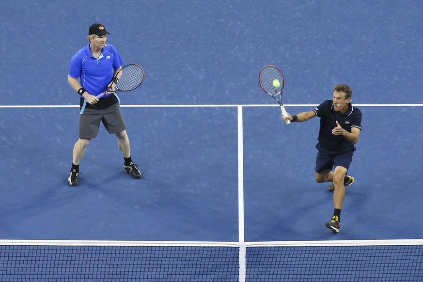 Mats Wilander, right, returns a shot to John McEnroe and James Blake, alongside Jim Courier during an exhibition doubles match at the U.S. Open tennis tournament, Thursday, Sept. 4, 2014, in New York. ...