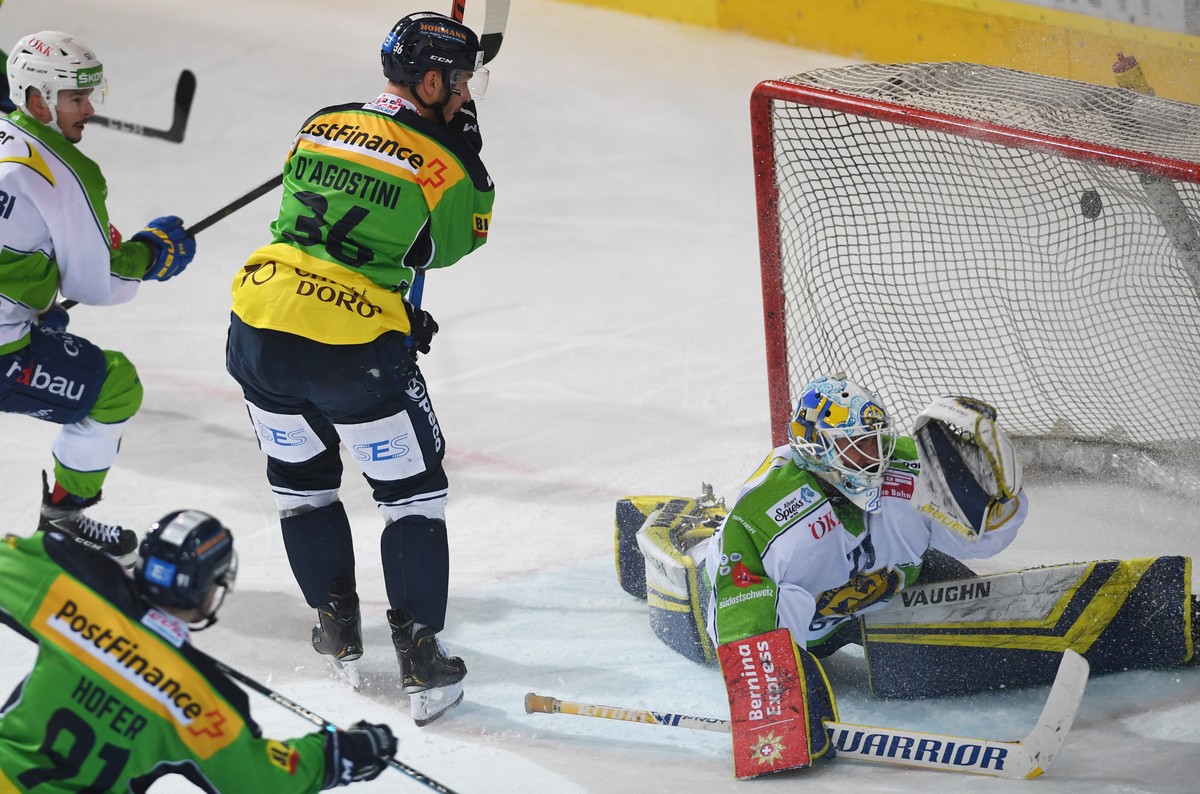 From left, Ambri's player Fabio Hofer scores the 1-1 goal, Ambri's player Matt D'Agostini, center and Davos's goalkeeper Sandro Aeschlimann, during the preliminary round game of Na ...
