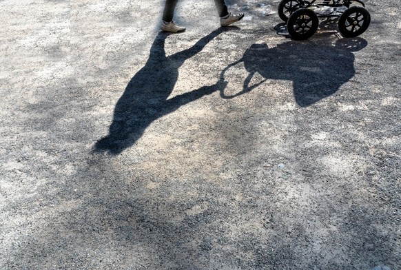 Frau schiebt Kinderwagen Schatten