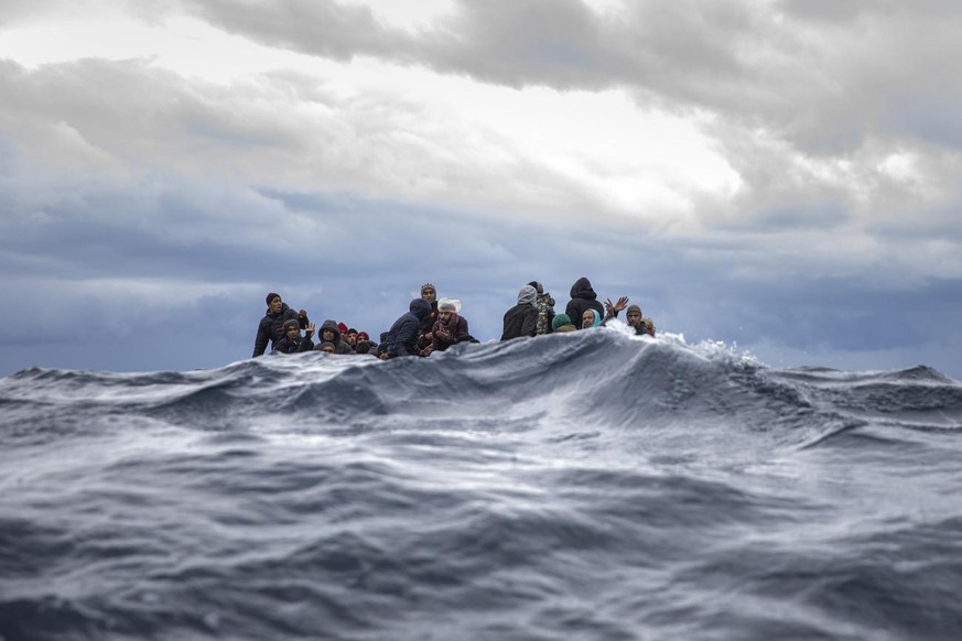 Men from Morocco and Bangladesh react on an overcrowded wooden boat, as aid workers of the Spanish NGO Open Arms approach them in the Mediterranean Sea, international waters, off the Libyan coast, Fri ...